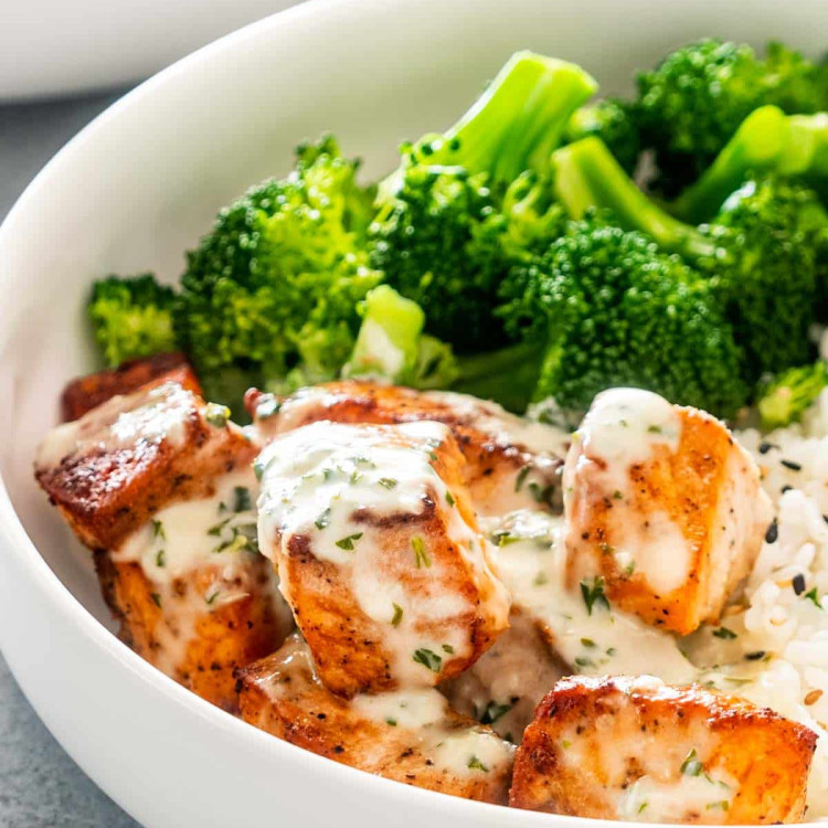 air fryer salmon with creamy garlic sauce in a white bowl with rice and broccoli.