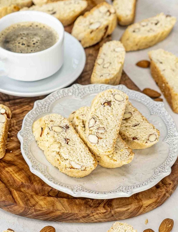 almond biscotti with a cup of coffee on a cutting board.