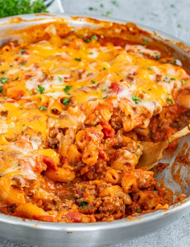 beefaroni topped with cheese and garnished with parsley in a skillet.