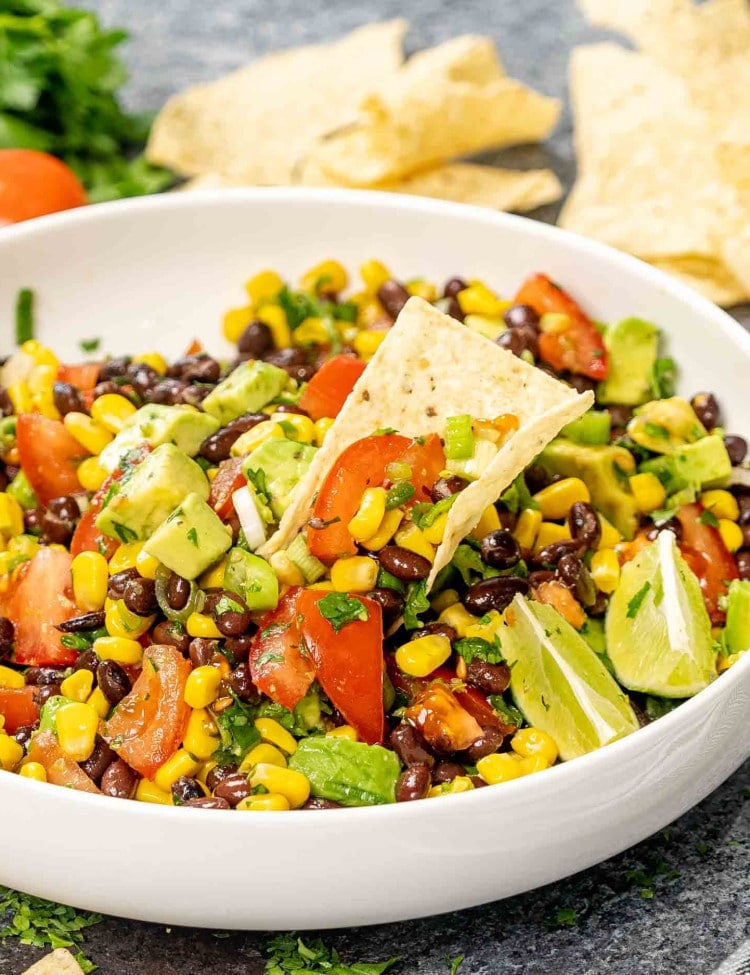 black bean corn avocado salad in a white bowl garnished with cilantro.