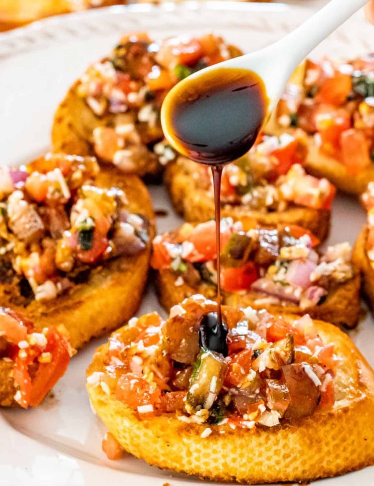 bruschetta on toasted baguette on a white platter.