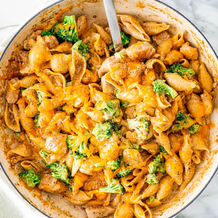 overhead shot of cheesy chicken broccoli pasta in a pot with a serving spoon taking a scoop