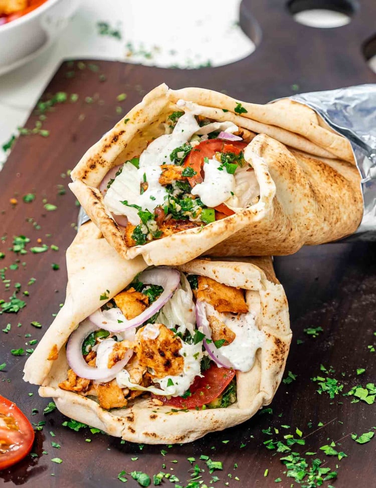 two chicken doner kebabs on a cutting board with a delicious yogurt sauce.