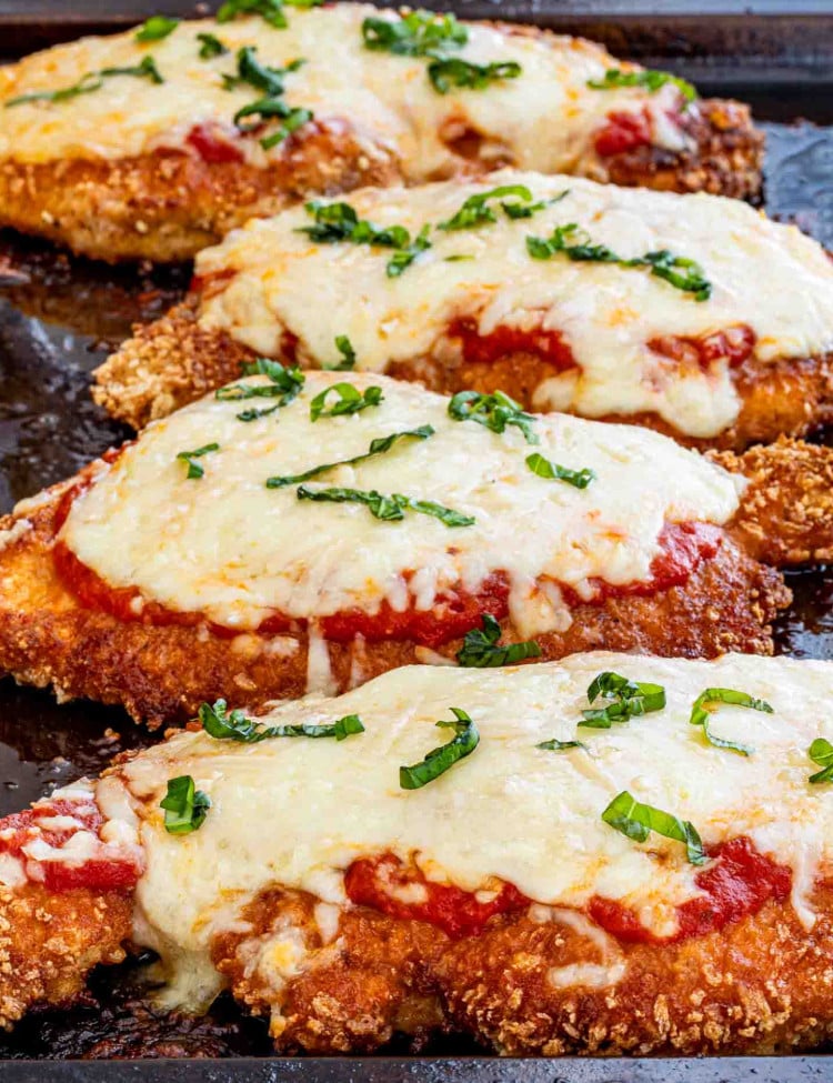 chicken parmesan fresh out of the oven on a baking sheet.