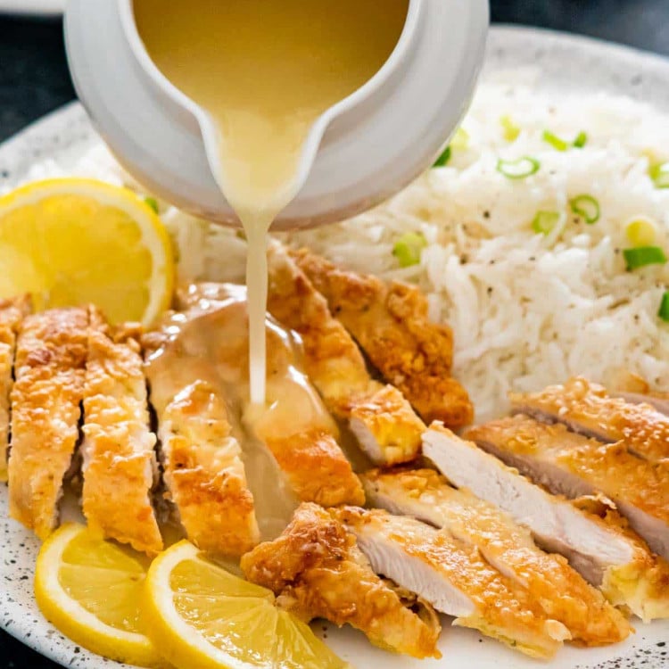 pouring lemon sauce over fried chicken.