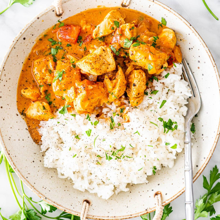 overhead shot of coconut chicken curry beside white rice in a bowl