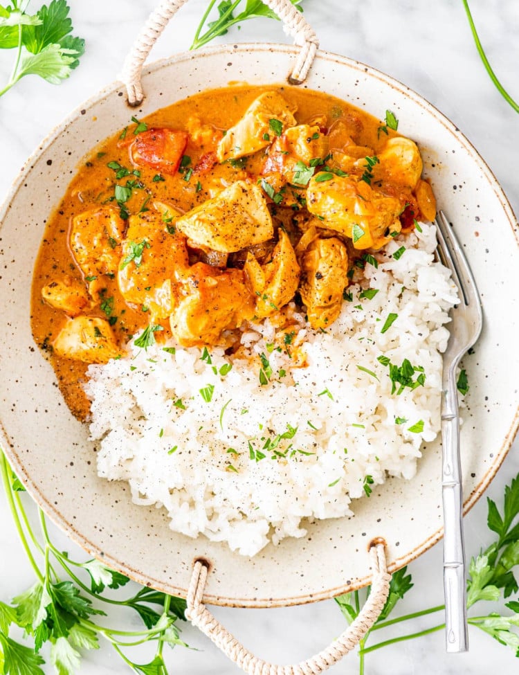 overhead shot of coconut chicken curry beside white rice in a bowl