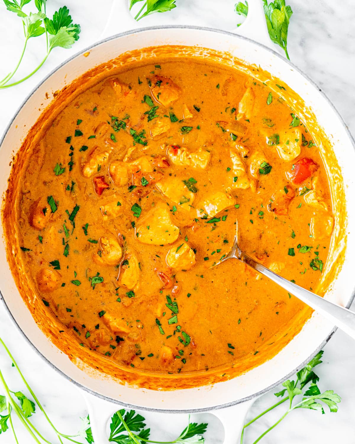 overhead shot of Coconut Chicken Curry in a dutch oven garnished with parsley