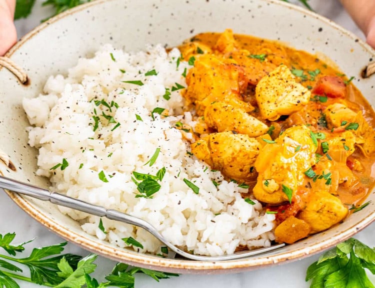 side view shot of a bowl filled with rice and coconut chicken curry