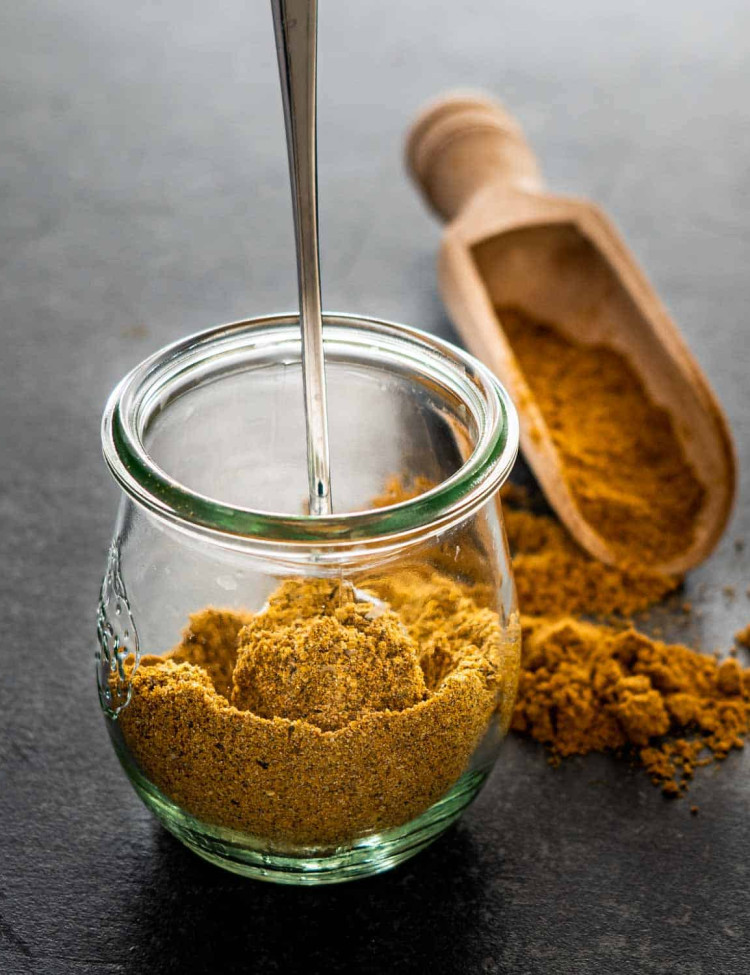 curry powder in a tulip jar with a spoon inside.