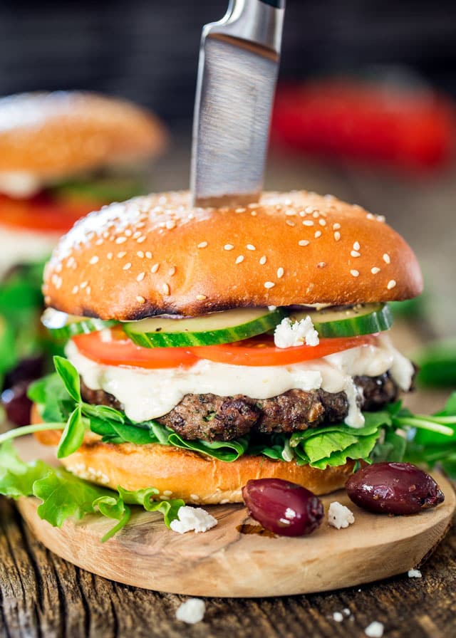 side view shot of a greek lamb burger with a knife stuck in the top