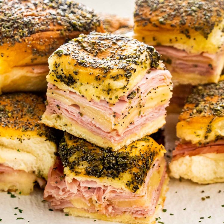 a few stacked ham and cheese sliders on a plate.