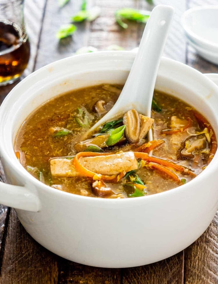 hot and sour soup in a white bowl with a white spoon inside.