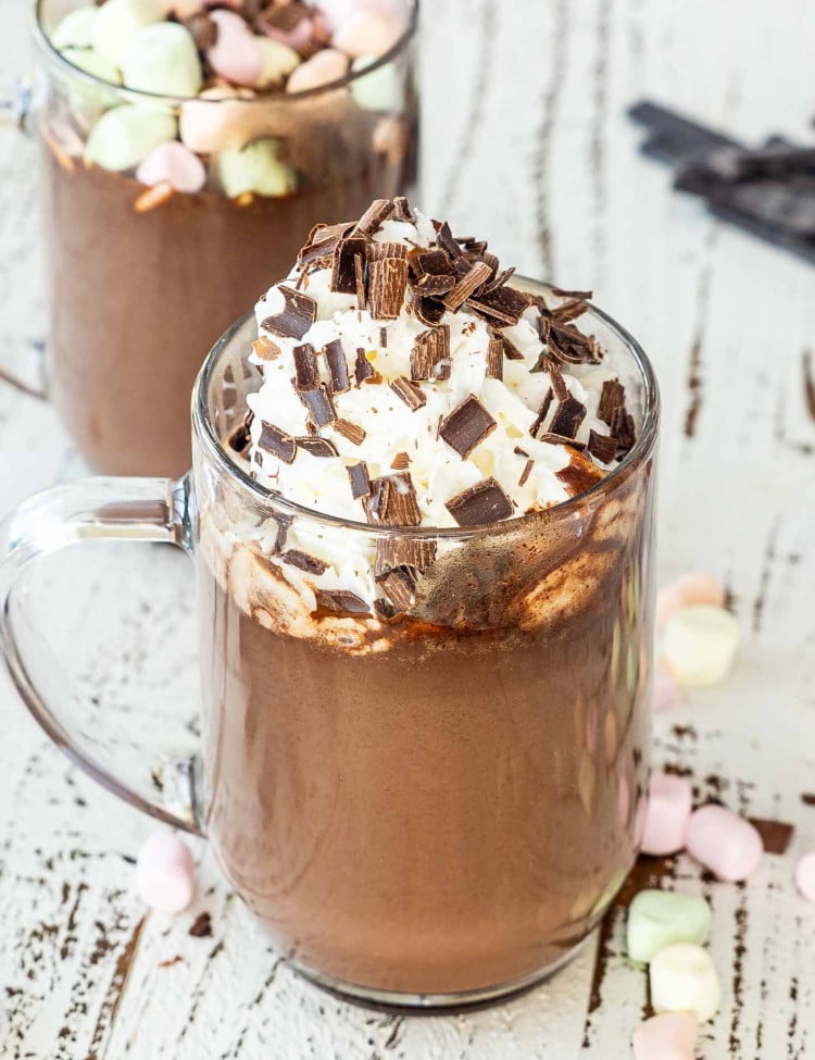 a hot chocolate in a mug topped with whipped cream and chocolate shavings.