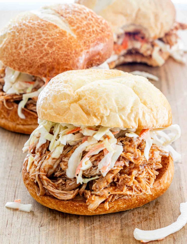 side view shot of a bbq pulled chicken sandwich with coleslaw on a cutting board.