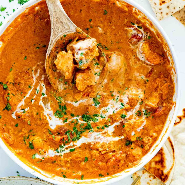 chicken tikka masala made in the instant pot in a white bowl with a wooden spoon inside.