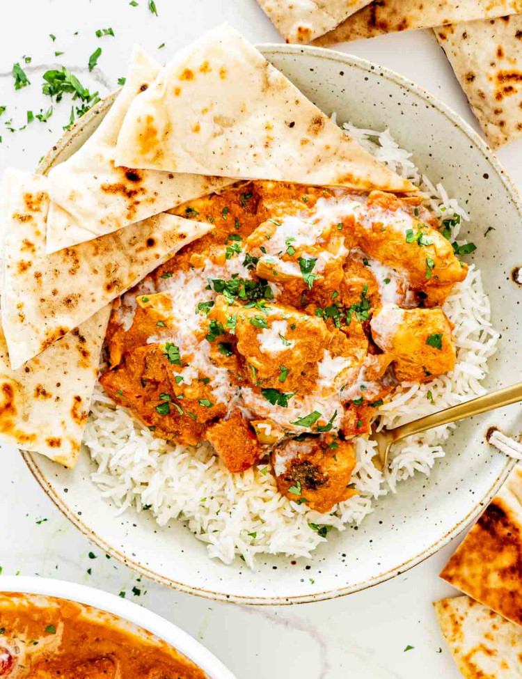 chicken tikka masala in a plate with rice and garnished with cilantro.