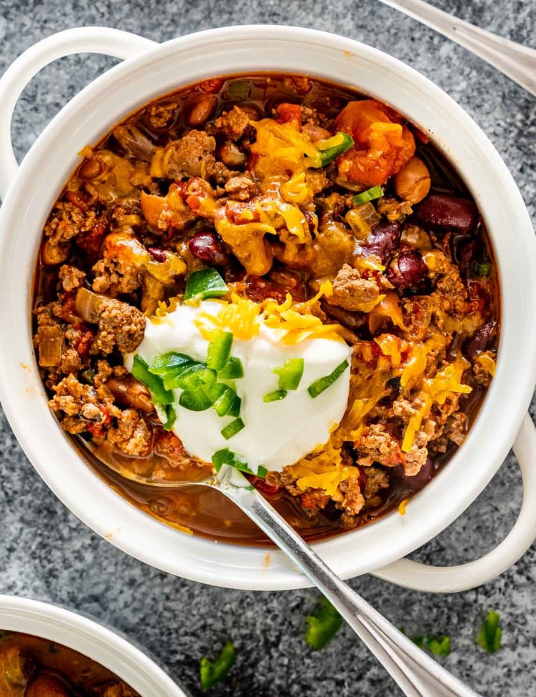 chili in a bowl topped with cheddar cheese and sour cream.