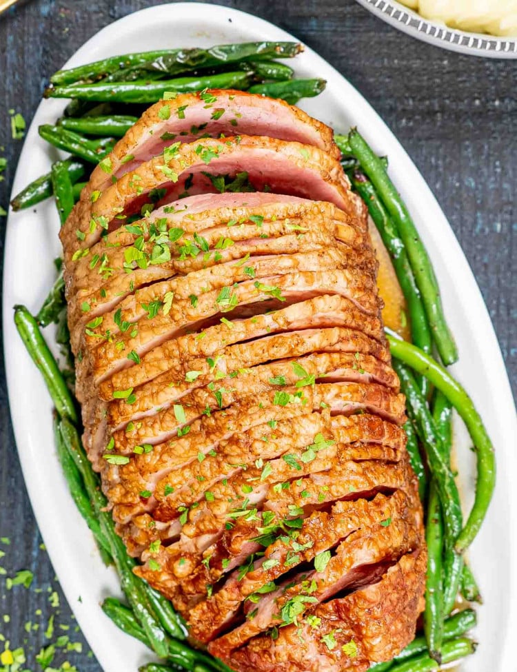 instant pot ham with green beans on a white platter.