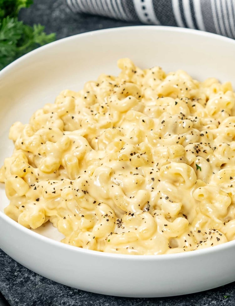 mac and cheese made in the instant pot in a white bowl garnished with salt and pepper.