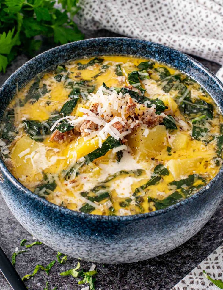 a blue bowl of zuppa toscana that was made in the instant pot.