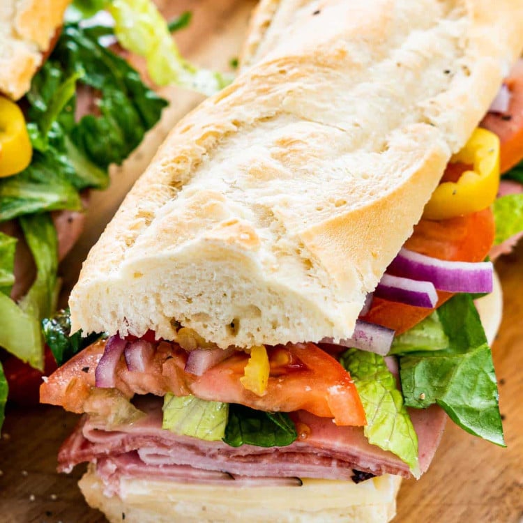 closeup of a freshly made italian sub on a cutting board.