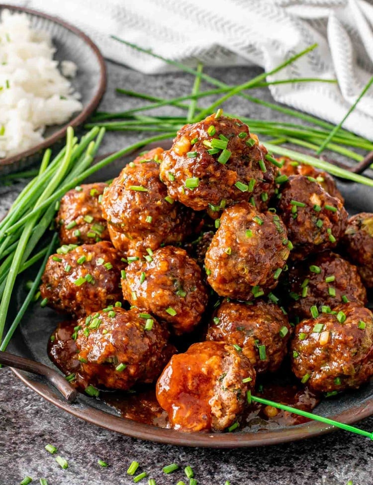 korean meatballs on a metal plate garnished with chives.