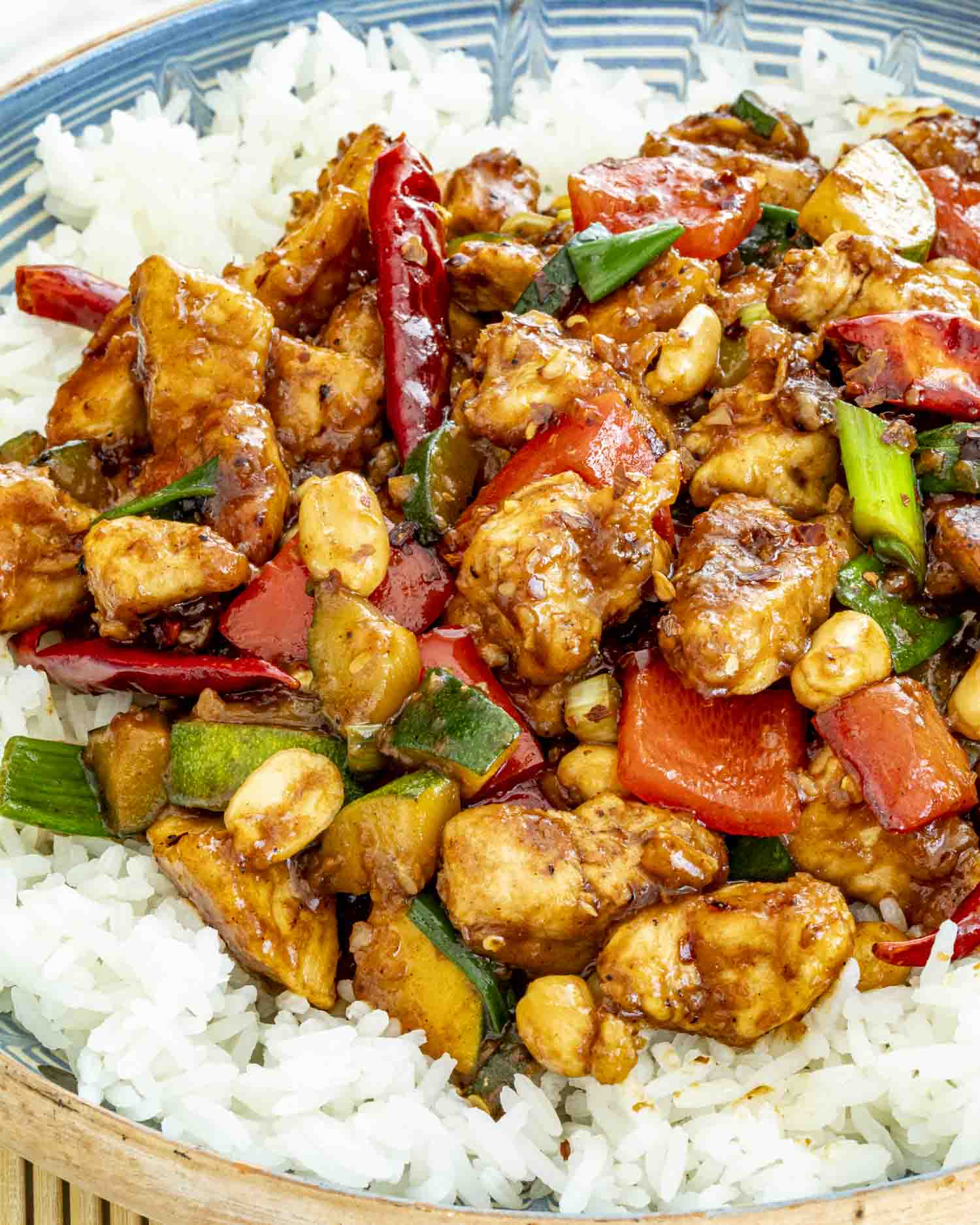 kung pao chicken over a bed of rice with 2 chopsticks.