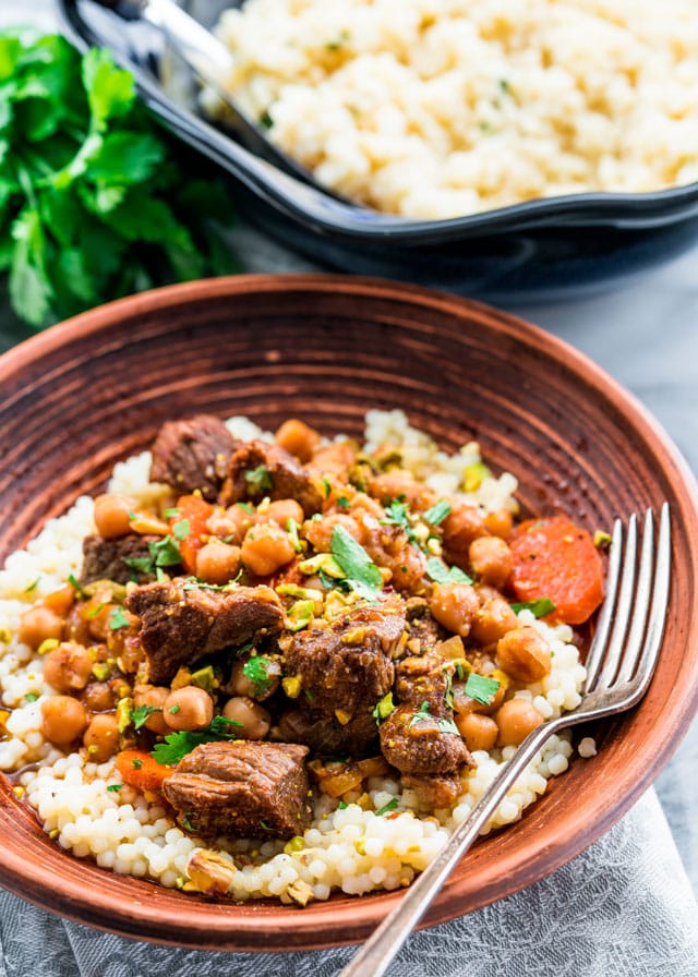 side view shot of a bowl of couscous topped with lamb and chickpea tagine