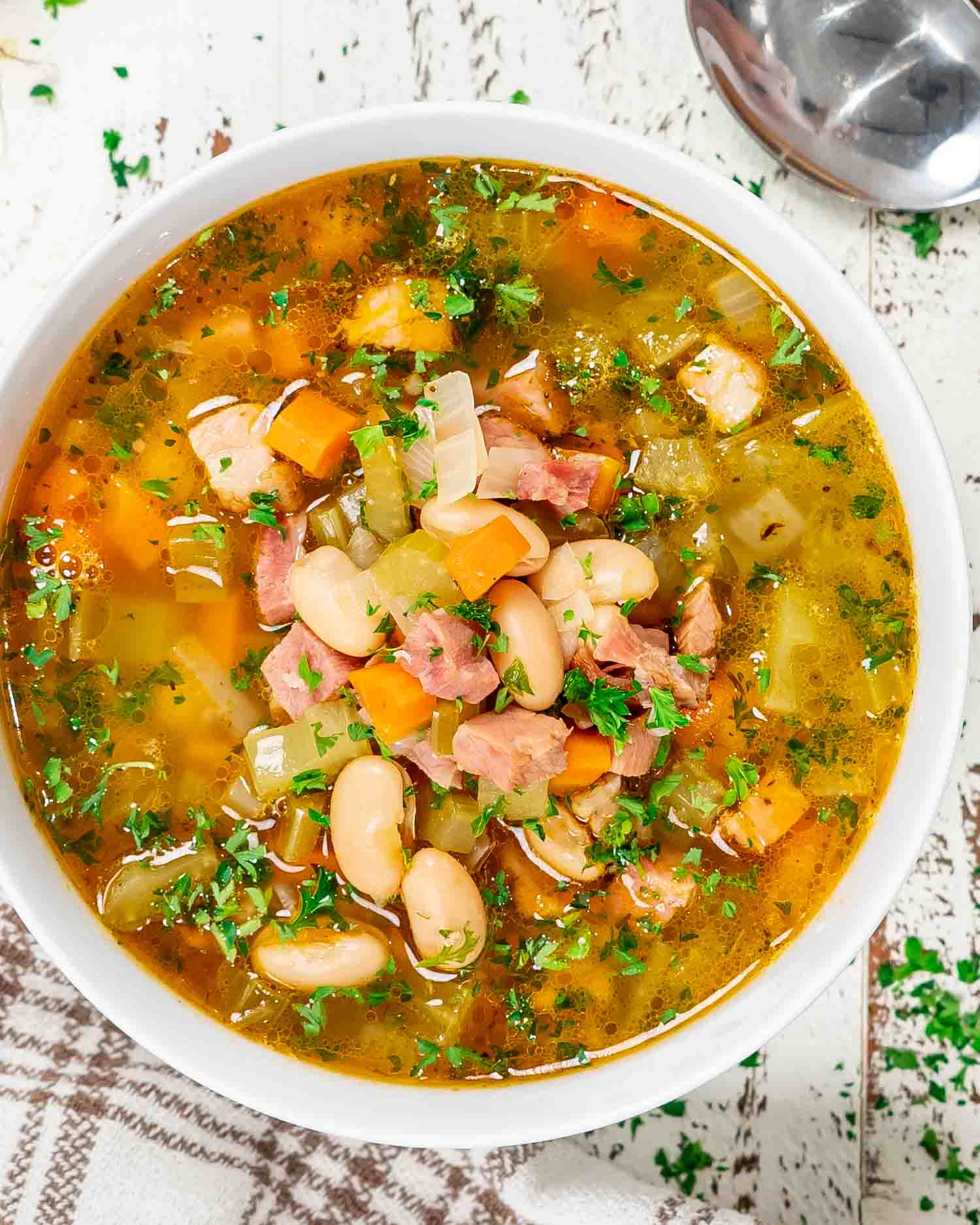 leftover ham and bean soup in a white bowl.