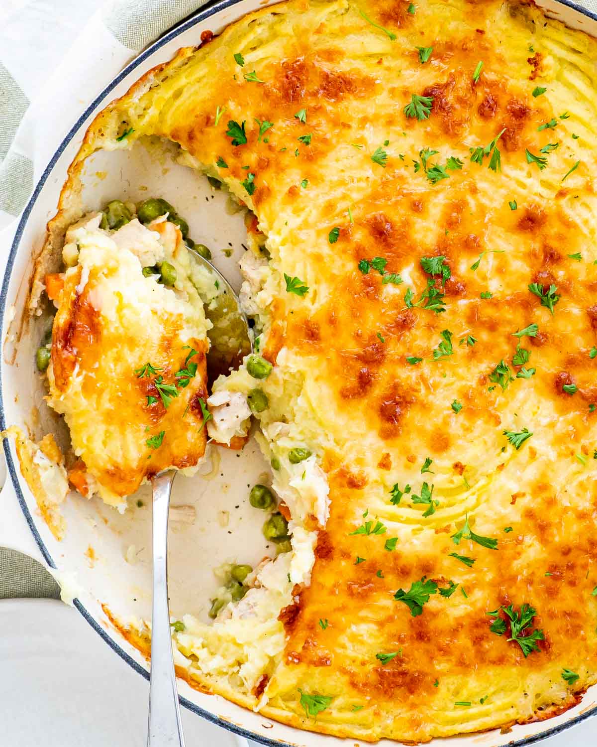 overhead shot of leftover turkey shepherd's pie in a skillet with a serving spoon.