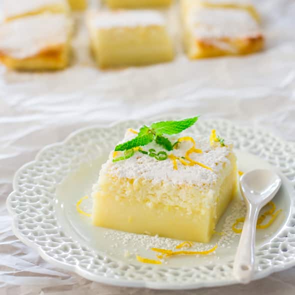 a slice of lemon magic cake dusted with powdered sugar on a plate