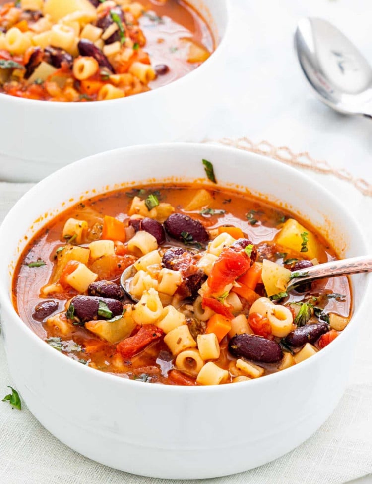 a spoon lifting minestrone soup from the bowl