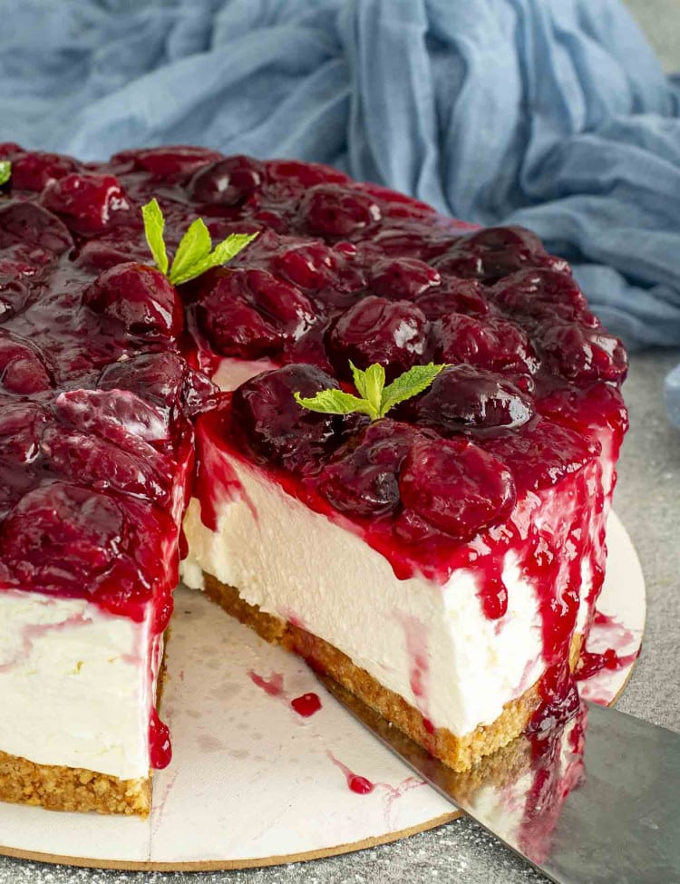 a no bake cheesecake topped with cherry pie filling on a platter.