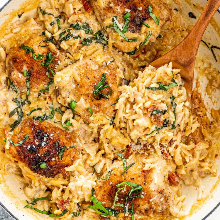 one pot chicken and orzo with a wooden spoon in it.