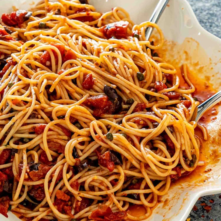 pasta puttanesca in a white serving bowl.