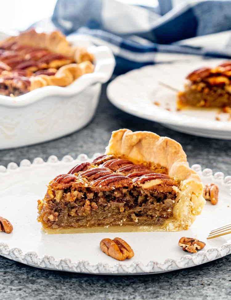 a slice of pecan pie on a white dessert plate.