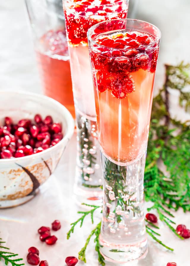 sparkling pomegranate elderflower cocktails with pomegranate floating in it