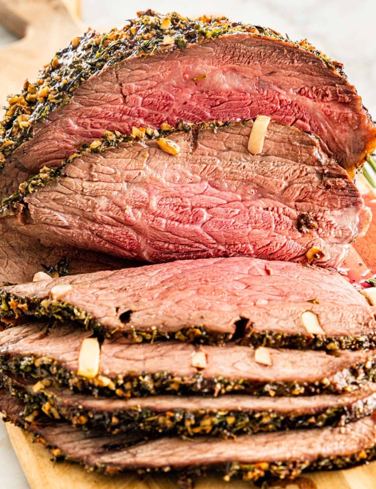 a piece of roast beef cut into slices on a cutting board