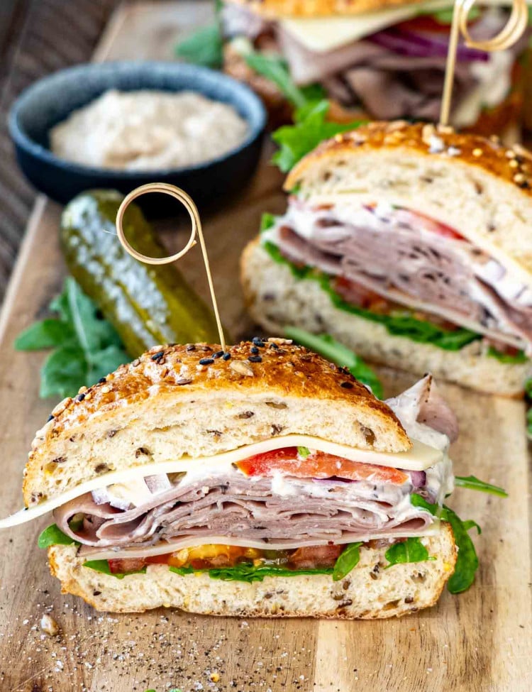 a roast beef sandwich cut in half on a cutting board.