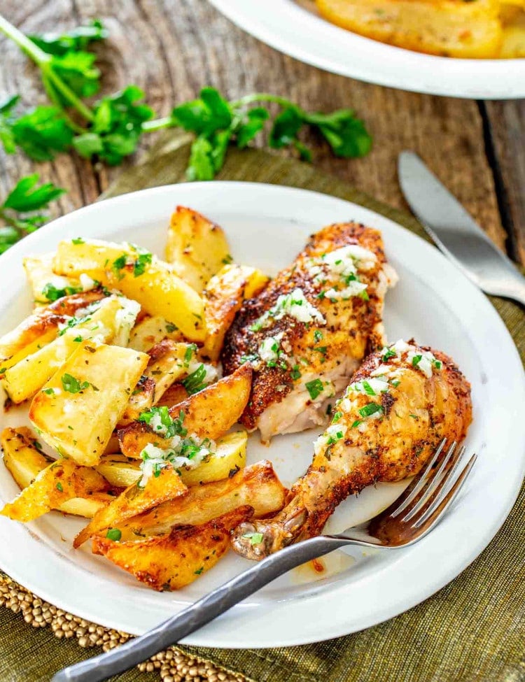 a serving of roasted chicken and potatoes on a white plate.