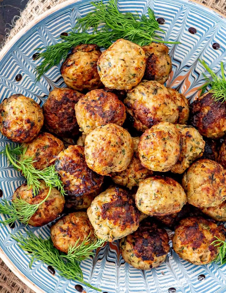 romanian meatballs in a clay bowl garnished with dill.