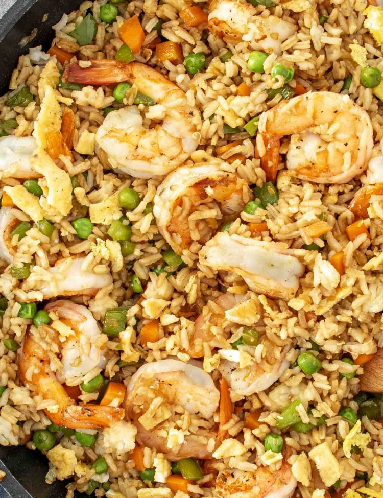 A close-up of shrimp fried rice, featuring plump shrimp, fluffy rice, peas, diced carrots, and scrambled eggs.