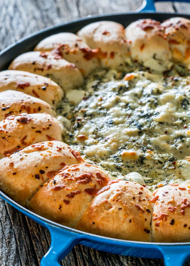 Spinach and Artichoke Dip in a blue pan with bread rolls