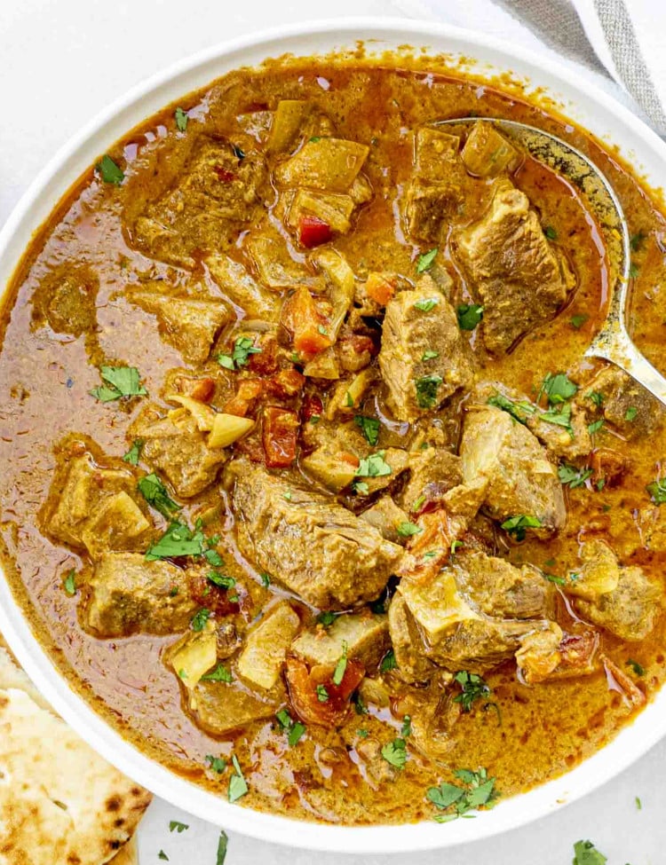 slow cooker beef madras in a white serving bowl garnished with cilantro.