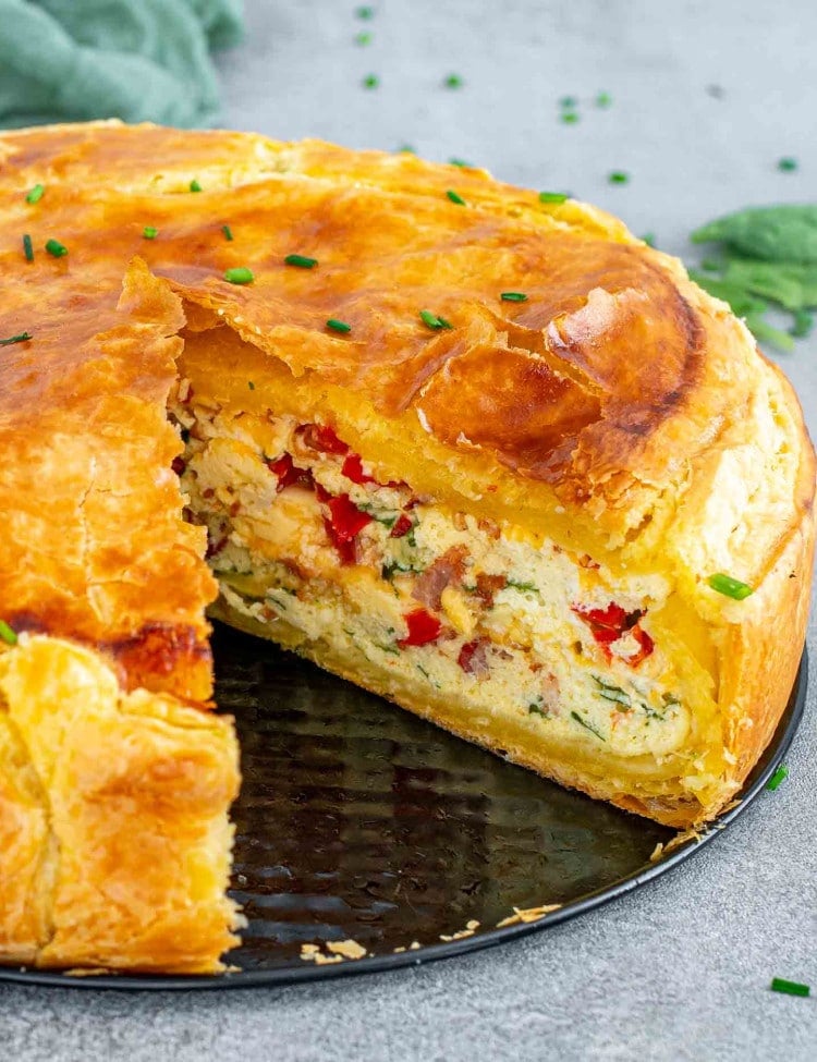 a spinach ricotta brunch bake pie with a slice cut out of it.