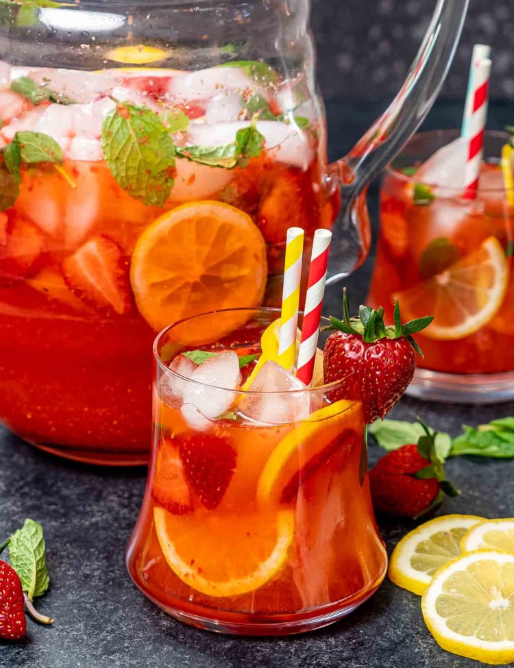 two glasses filled with strawberry lemonade garnished with lemon slices and strawberries.