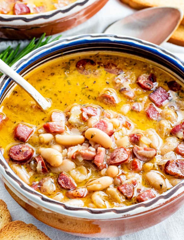 sideview shot of a tuscan bean soup in a clay bowl with a spoon inside