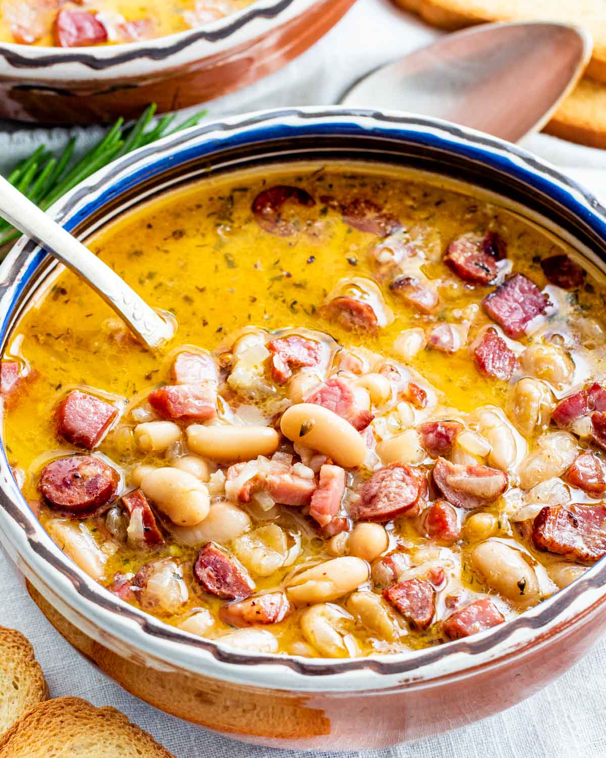 sideview shot of a tuscan bean soup in a clay bowl with a spoon inside