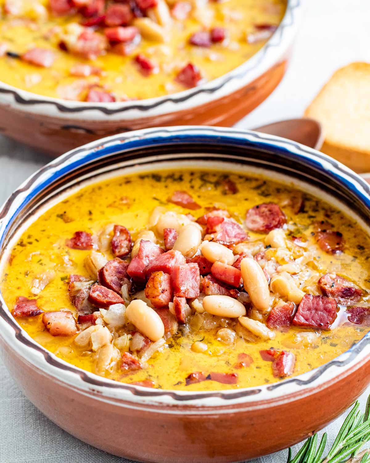 sideview shot of a tuscan bean soup in a clay bowl and another bowl in the background